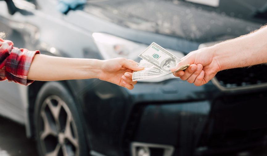 cropped view of man giving money to woman near car cropped view of man giving money to woman near car
