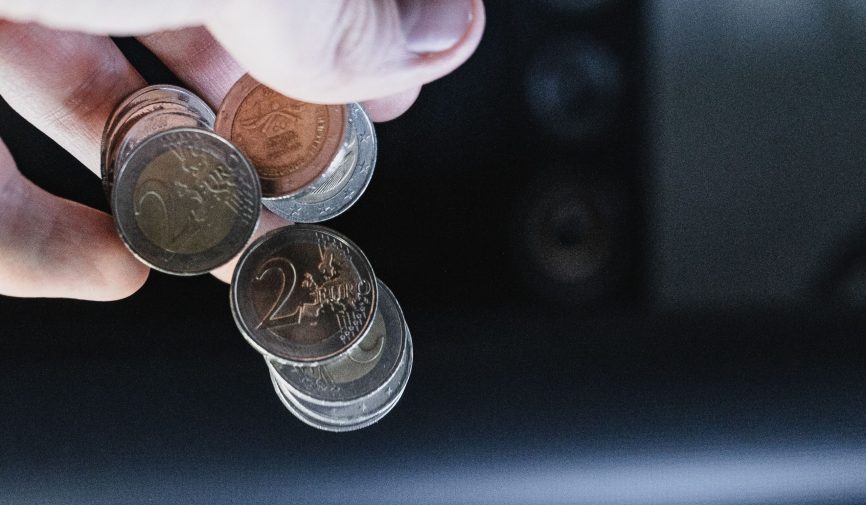Closeup shot of a hand pouring out a couple of two Euro coins Closeup shot of a hand pouring out a couple of two Euro coins