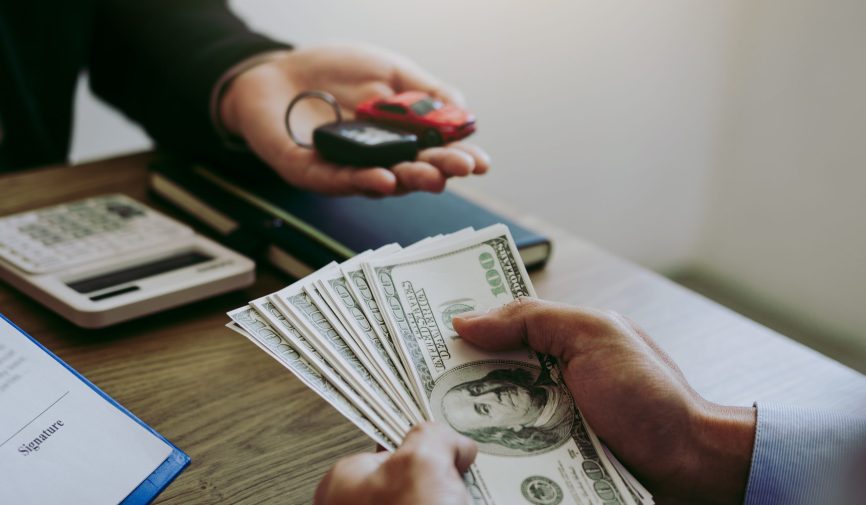 New car buyers are holding cash and handing it to car salespeopl New car buyers are holding cash and handing it to car salespeopl