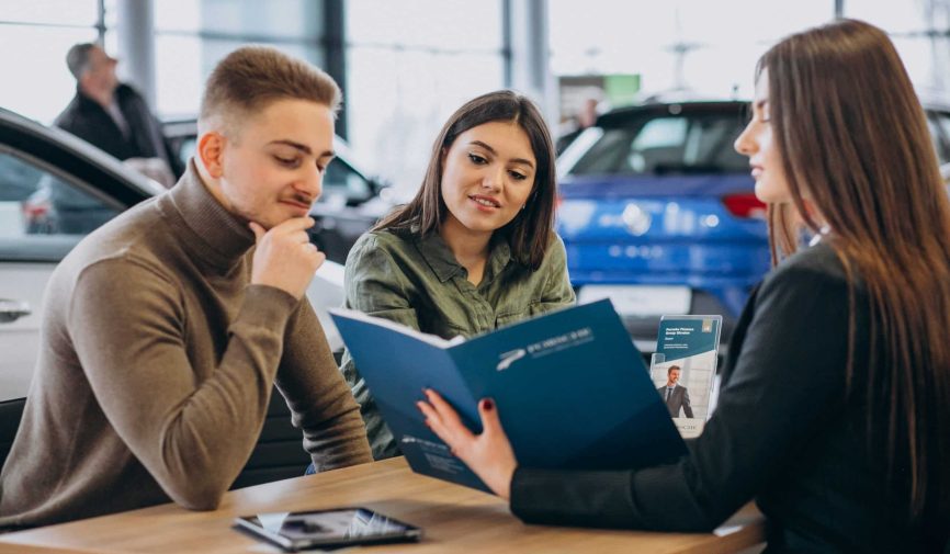 Young couple talking to a sales person in a car showroom Young couple talking to a sales person in a car showroom