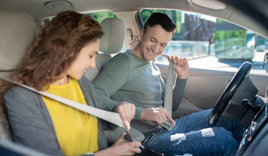 Young couple sitting in the car, woman fixing her safety belt Collage of people buying, selling, and driving cars including luxury vehicles, electric cars, car dealerships, and family car transactions.