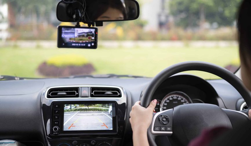 Woman driving in reverse and using a rear view camera in her car Collage of people buying, selling, and driving cars including luxury vehicles, electric cars, car dealerships, and family car transactions.