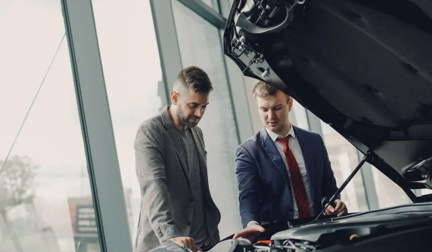 selling-inherited-car-dublin-probate Two men inspecting a car's engine hood in a dealership showroom